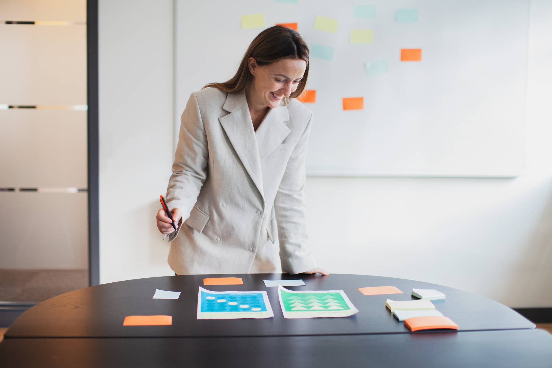 Kvinna står vid ett skrivbord framför en whiteboard med post-it-lappar.