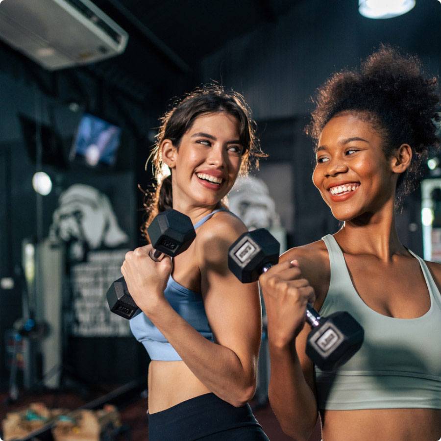 2 people with weights in a gym, looking happy. 